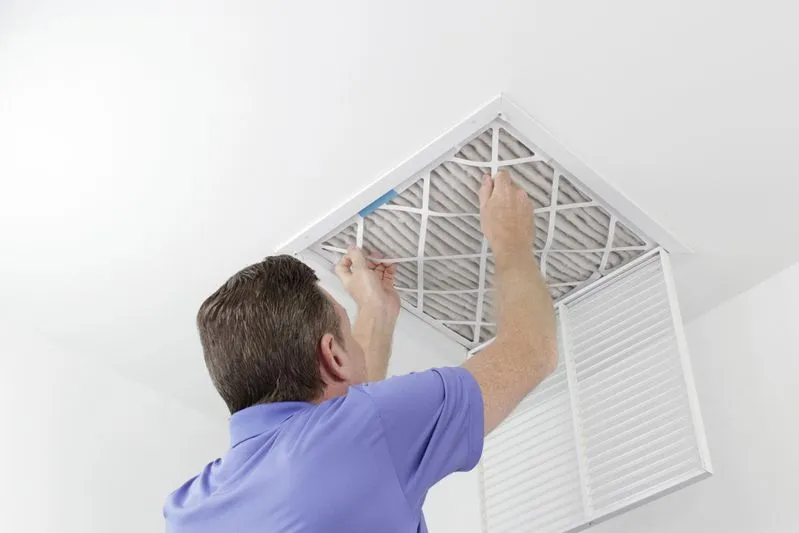 Home 4 An image of a professional replacing a ceiling-mounted furnace air filter, ensuring optimal heating system performance.