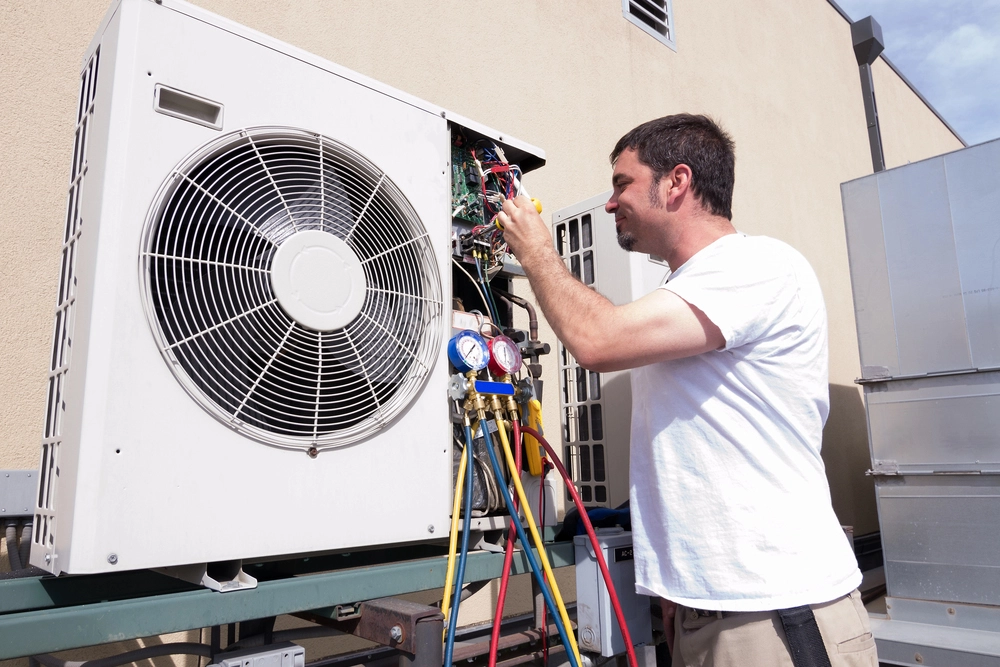 Home 5 An image of an HVAC technician inspecting ventilation and wiring on a rooftop unit to improve indoor air quality and airflow.
